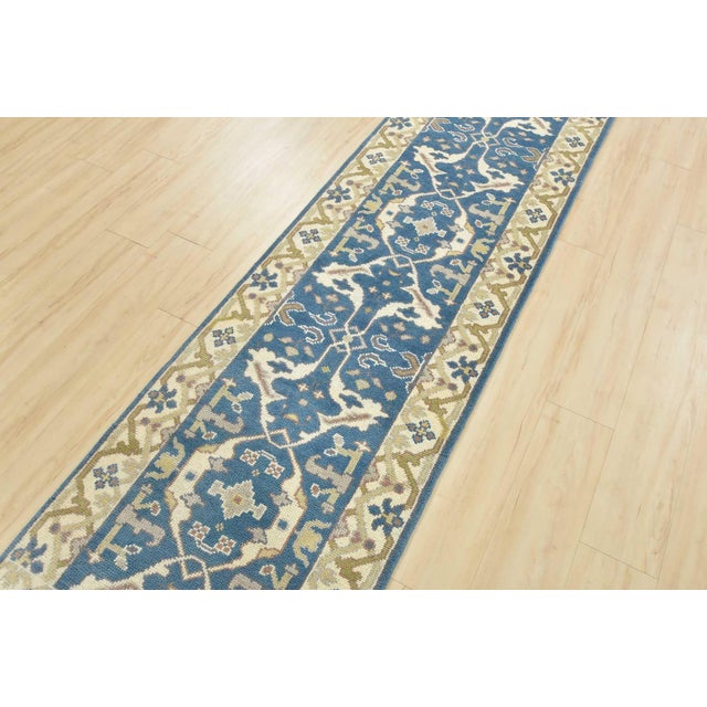 A modern tribal Oushak runner hand-knotted with an all-wool pile on a cotton foundation. This oriental rug features a...