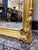 A striking French-style mirror featuring an elaborate scroll top and decorative sides. The frame is fully gilded, giving...