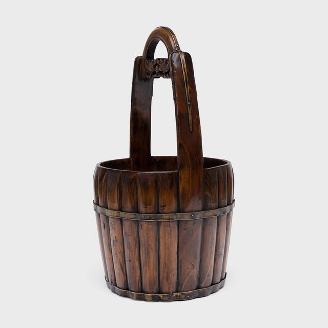 Finely crafted of elmwood and brass, this lovely wooden bucket is a 19th-century Chinese water pail used for drawing up...