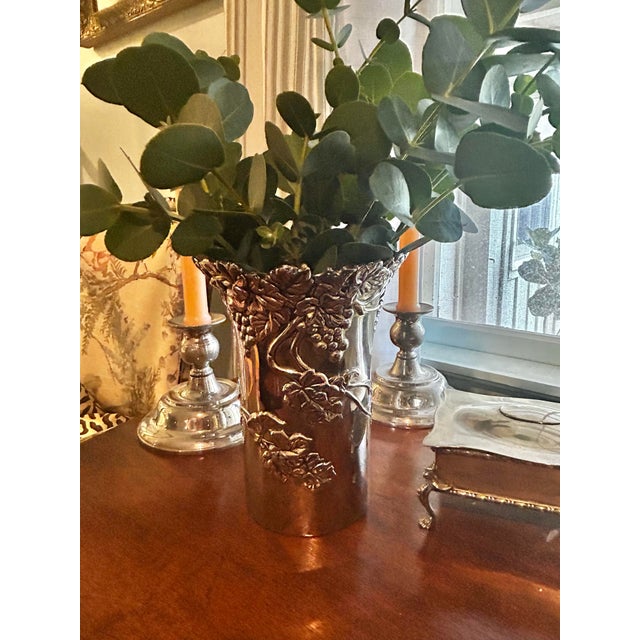 A richly detailed silver-plated brass vase by Vera Lucino featuring sculptural grapevines, curling tendrils, and clusters...