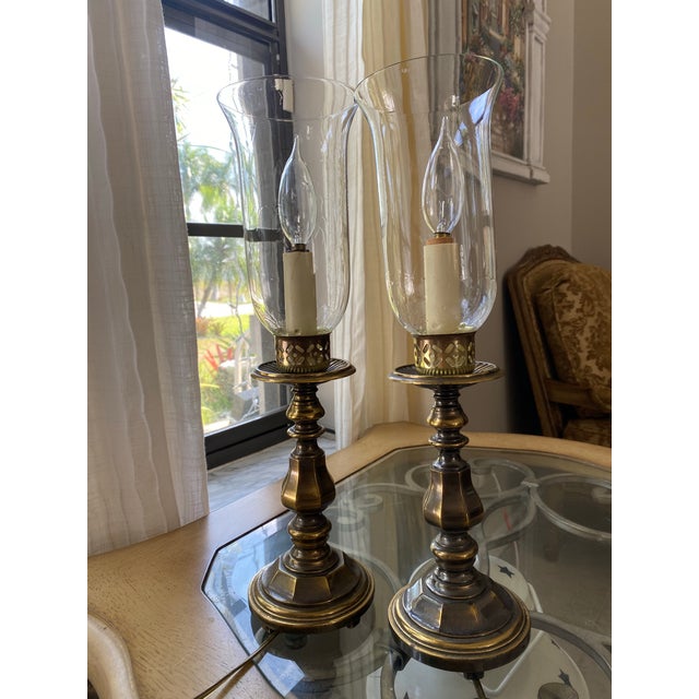 vintage brass and glass hurricane lamp featuring a classic patinated base and a clear glass chimney. Excelente condition