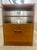 Mid-century modern teak file cabinet with open shelves and a single lockable drawer. It features clean lines and the warm...
