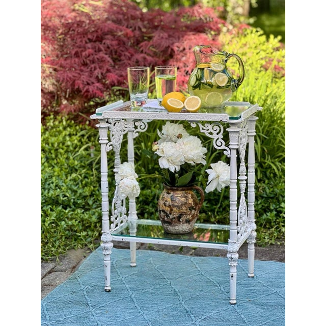 Beaux Arts cast iron two-tier glass top garden table with white paint patina, France, circa 1880. An exquisite table of...