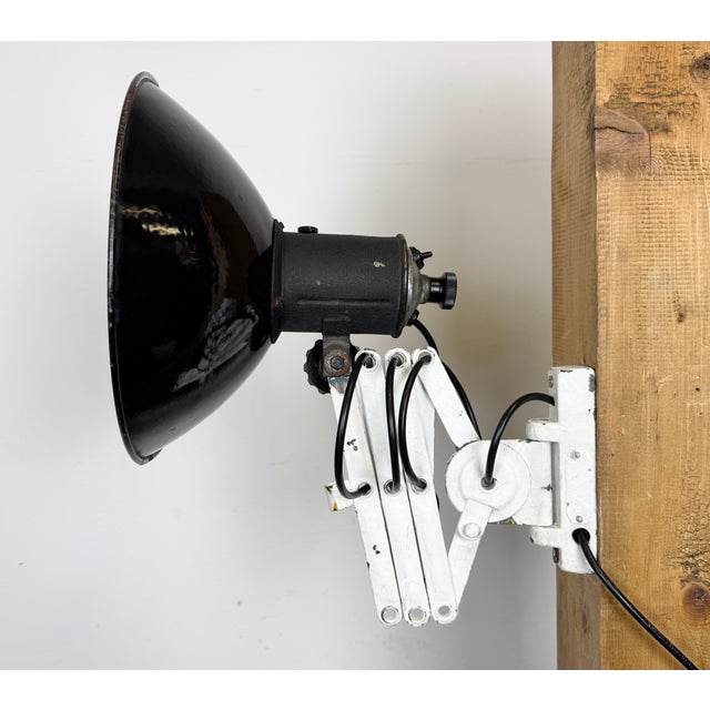 This vintage industrial adjustable scissor wall lamp was produced in former Czechoslovakia during the 1950s. The lamp has...