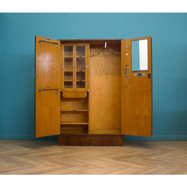 1930s oak compactum with bold geometric veneer and original brass handles. Fitted interior: hanging rail to the right; to...