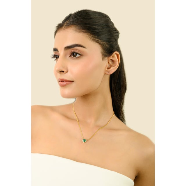 This elegant heart-shaped pendant features a natural emerald weighing 1.29 carats, measuring approximately 7 x 7.5 mm. The...