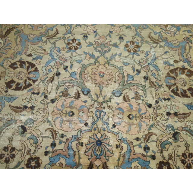 An early 20th century Persian Tabriz rug with light blue and brown dominant accents on an off white field, green border....