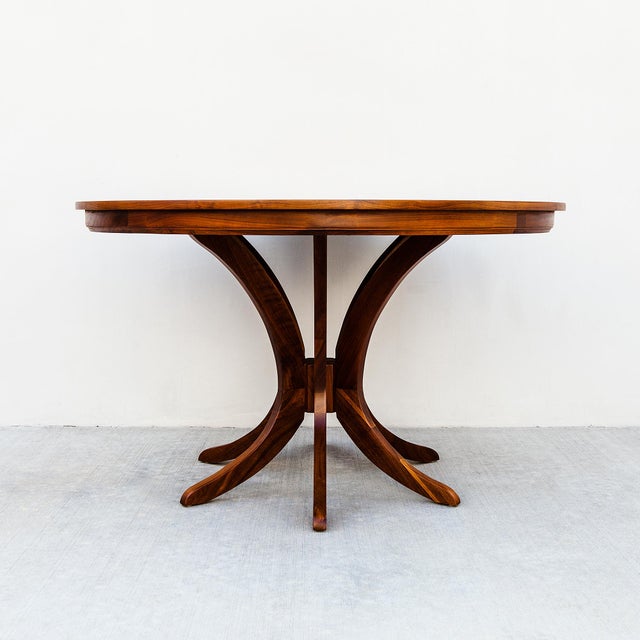 A beautifully refinished expandable walnut dining table with two leaf extensions from the 1960s. The tabletop rests atop...