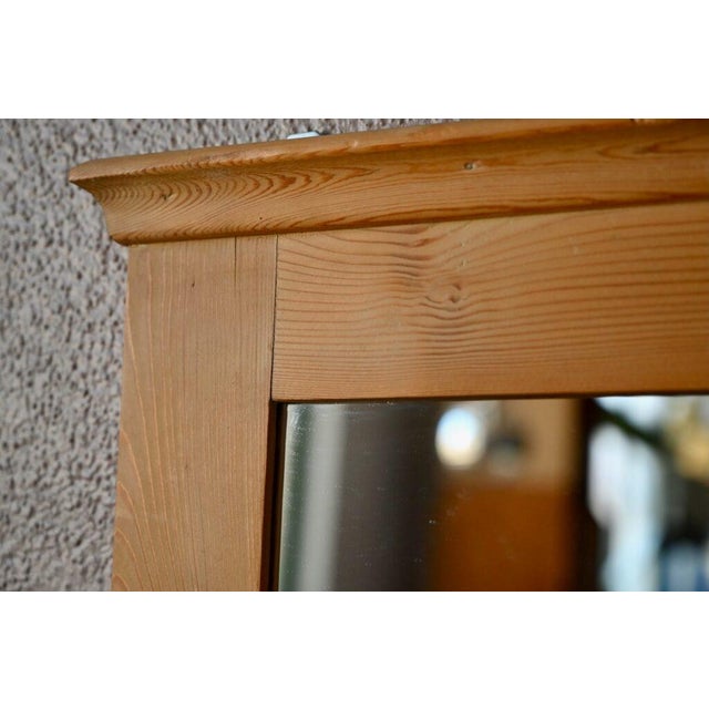 This generously sized mirror features an elegant wooden frame. It once adorned a rustic piece of furniture. It has a...