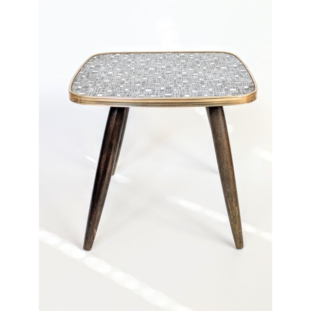 A stylish vintage 1960s square flower stand with four wooden legs, featuring a black and white linoleum top with a...