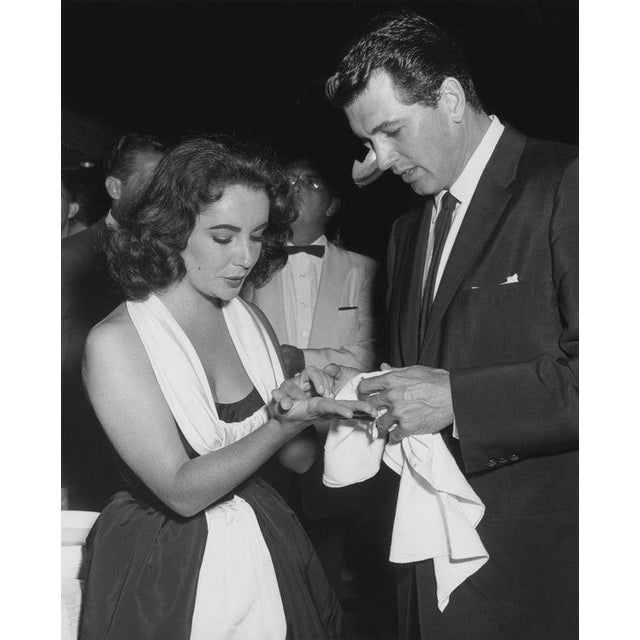 Elizabeth Taylor And Rock Hudson American actor Rock Hudson (1925 - 1985) dries the hands of actress Elizabeth Taylor...