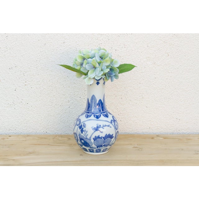 A single landscape scene, rockwork and clouds rendered in confident cobalt brushwork, wraps the lower body, left to...