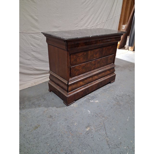 Elegant French Restoration period commode crafted in richly figured walnut and topped with a substantial gray marble slab...