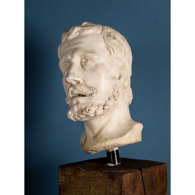 An elegant marble male head, with a finely sculpted beard and wavy hair, depicts a figure with his face turned heavenward,...
