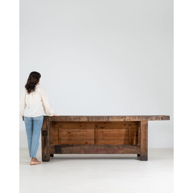 A substantial carpenter’s work table reflecting traditional workshop craftsmanship, featuring a long solid wood top built...