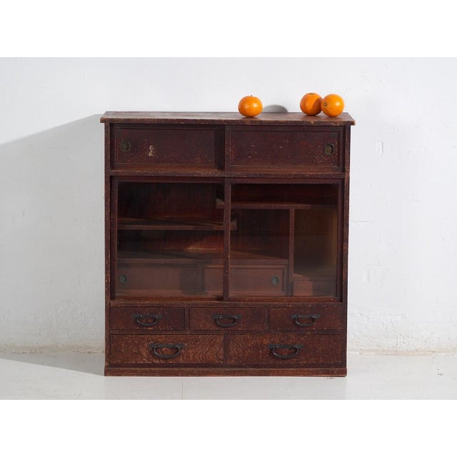 Antique japanese glass display cabinet with sliding glass doors and multiple drawers, made of solid wood and glass and...