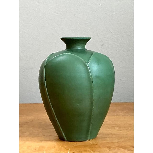 This vintage ceramic vase presents a gently bulbous, egg-shaped body that swells generously before tapering into a...