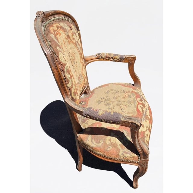 The French Louis XV Style Carved Walnut & Original Tapestry Upholstered Armchair (Fauteuil) is a quintessential example of...