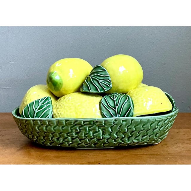 This trompe l'oeil centerpiece presents a generous mound of sculpted ceramic lemons, each rendered with convincing...