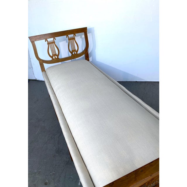 An early 19th-century fruitwood French bench with Double-Lyre splats in the Regency style. The bench has been recovered....