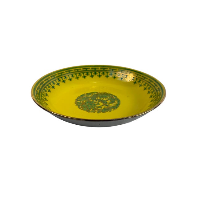 This is a mid 20th Century Chinese Export porcelain bowl featuring a vivid yellow ground with green decorative borders and...