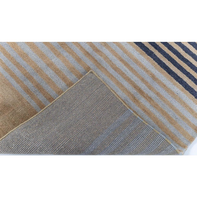 This modern Deco-inspired hand-knotted rug presents a refined composition of vertical stripes arranged in balanced,...