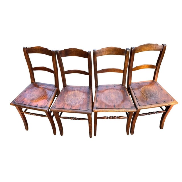 Set of four antique Luterma chairs made in Estonia, with warm amber-brown wood, curved backs, and ornate fan-and-scroll...
