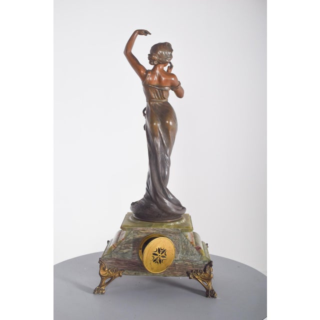French table clock with marble base and figure. French table clock, with a greenish marble base, topped by a lady's...