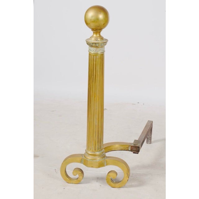 A commanding pair of 31-inch brass andirons combining classical fluted columns, oversized ball finials, and beautifully...