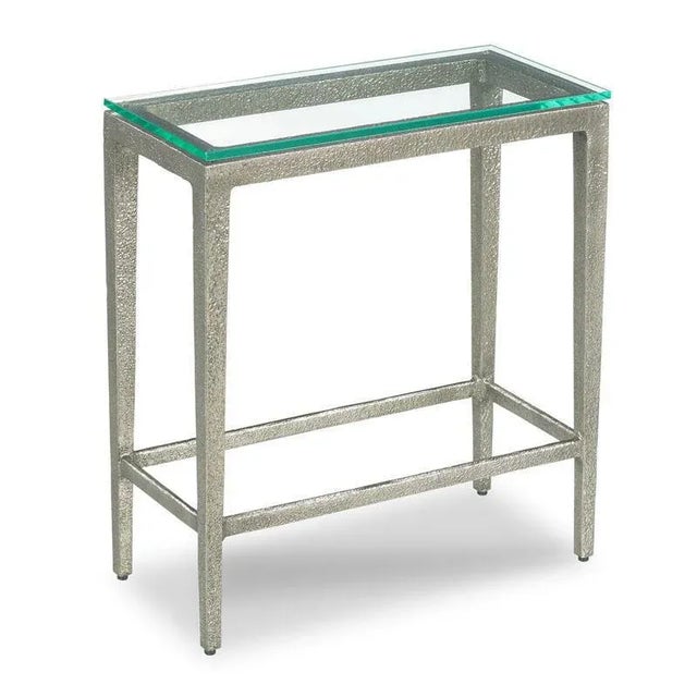 A petite table for drinks featuring a contemporary glass top above a textured silver metal base.