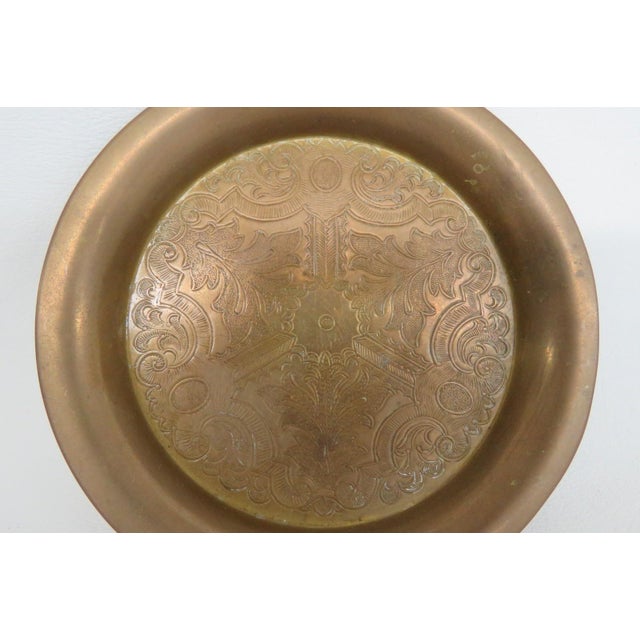 This Decorative Plate is made out of brass. This lovely small plate features a rounded shape, engraved floral details to...
