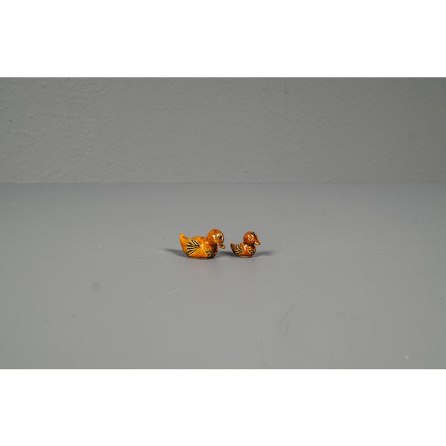 Decorative set of two glazed ceramic duck figures, consisting of one larger and one smaller piece. The ducks feature warm...