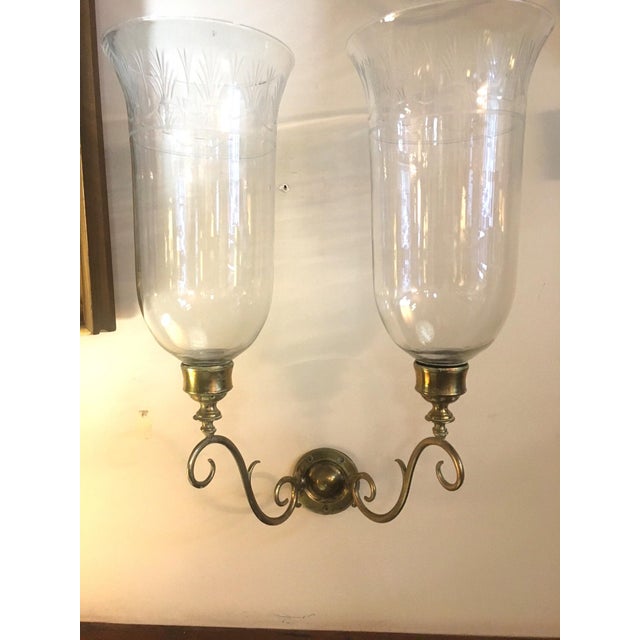 In the style of George III (1760-1820), this handsome pair of English double brass hurricane sconces feature graceful...