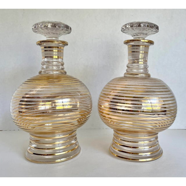 Here is an elegant pair of glass decanters with gold, linear stripes. The stoppers are cut glass and have a lovely design...
