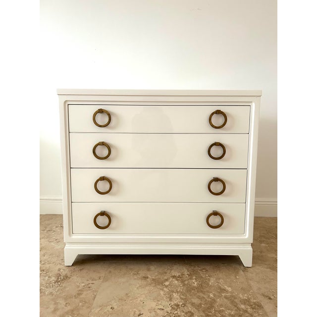 White lacquer chest of drawers featuring the original thick bronze hoop drawer pulls. Manufactured by United Furniture...