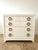 White lacquer chest of drawers featuring the original thick bronze hoop drawer pulls. Manufactured by United Furniture...