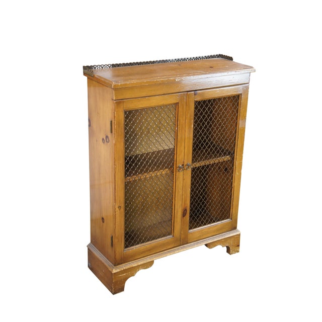A quaint farmhouse cabinet. Made from pine with two lattice front doors opening to an interior with one shelf. Features a...