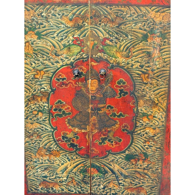 A commanding pair of large antique Tibetan wooden cabinet doors featuring hand-painted warrior figures amid intricate...