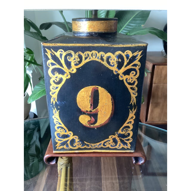Charming vintage folk art table lamp featuring a hand-painted “No. 9” framed by ornate gilt scrollwork on a brown scroll...