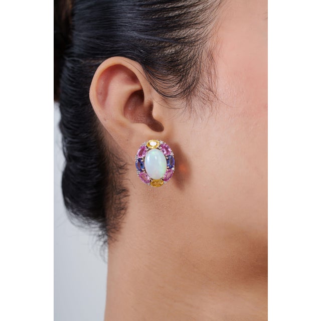 These cluster stud earrings feature 18.2-carat luminous oval cabochon opal multi sapphires, set in 18k white gold. The...