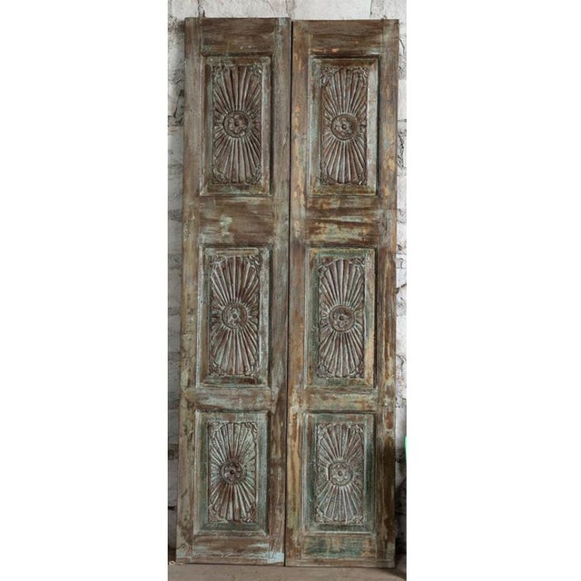 A striking vintage barn door featuring an intricate sunburst hand-carved design, crafted from solid reclaimed wood with a...