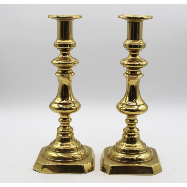 Circa 1860 pair of brass 11" candlesticks, English. Baluster form on chamfered corner square bases. Ring turned, built on...