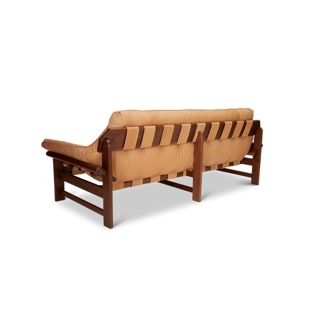 The Ojai sofa features a solid walnut base and a single tufted leather cushion with leather straps. The Lawson-Fenning...