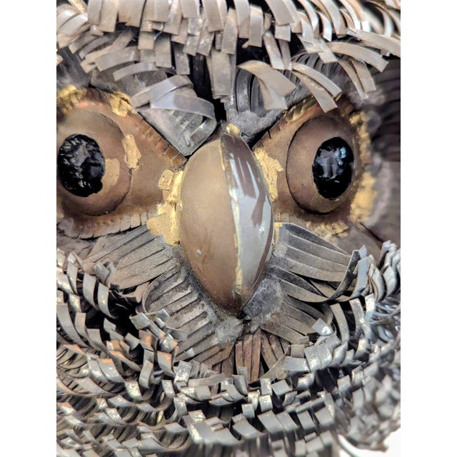 A heavily textured Brutalist owl sculpture constructed from torch-cut copper and brass elements welded over a wire frame....