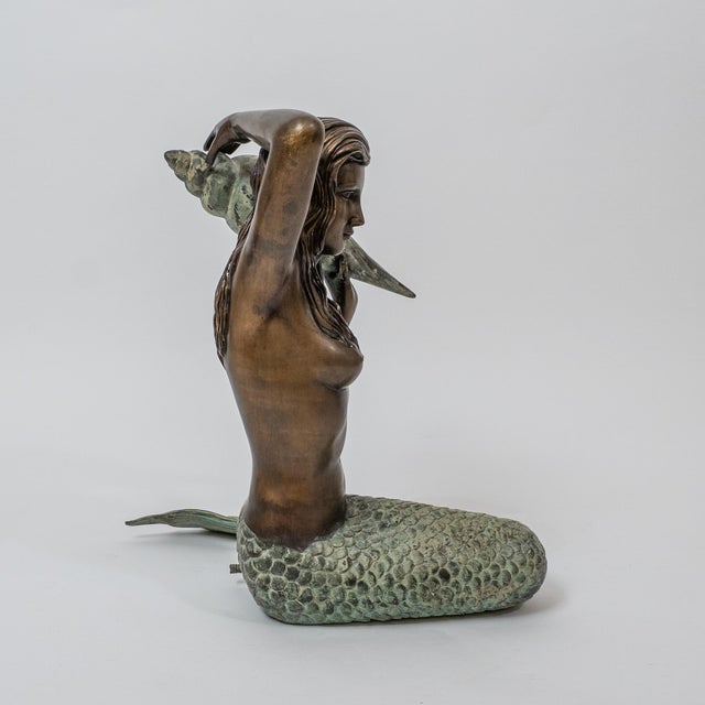 Mid-century cast bronze sculpture depicting a mermaid holding a large conch shell. Designed as a fountain figure with a...
