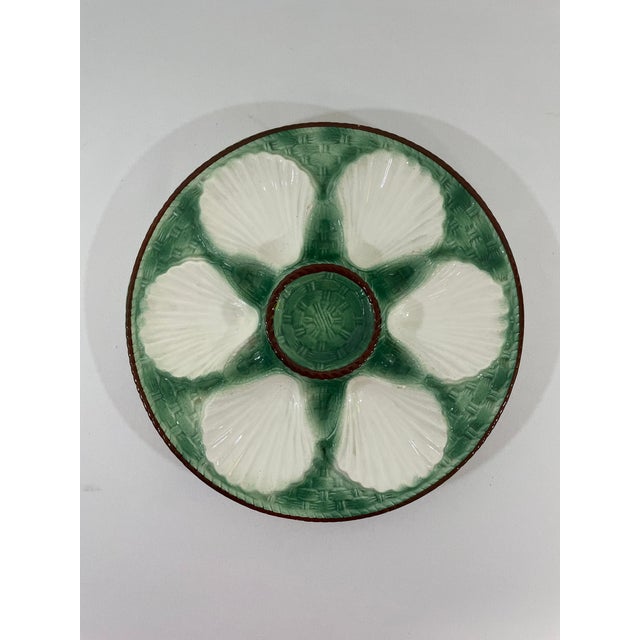 A striking antique French Faience Longchamp glazed majolica oyster plate with a vibrant green basket weave background and...