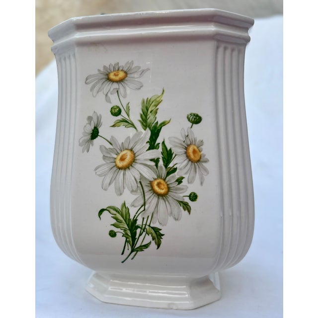 The distinct design of this white ceramic vase features a fluted body with ribbing on the four corners. Each flat side of...