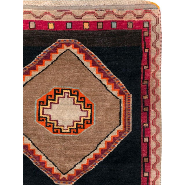 This Mid-20th century Turkish Anatolian gallery carpet presents a bold geometric composition arranged across a deep...