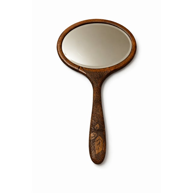 An elegant early 20th century hand mirror, finely carved from solid walnut and decorated with an intricate rose motif in...