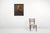 An oil painting of a solitary man seated at a rustic wooden table, exuding an air of contemplation and introspection....